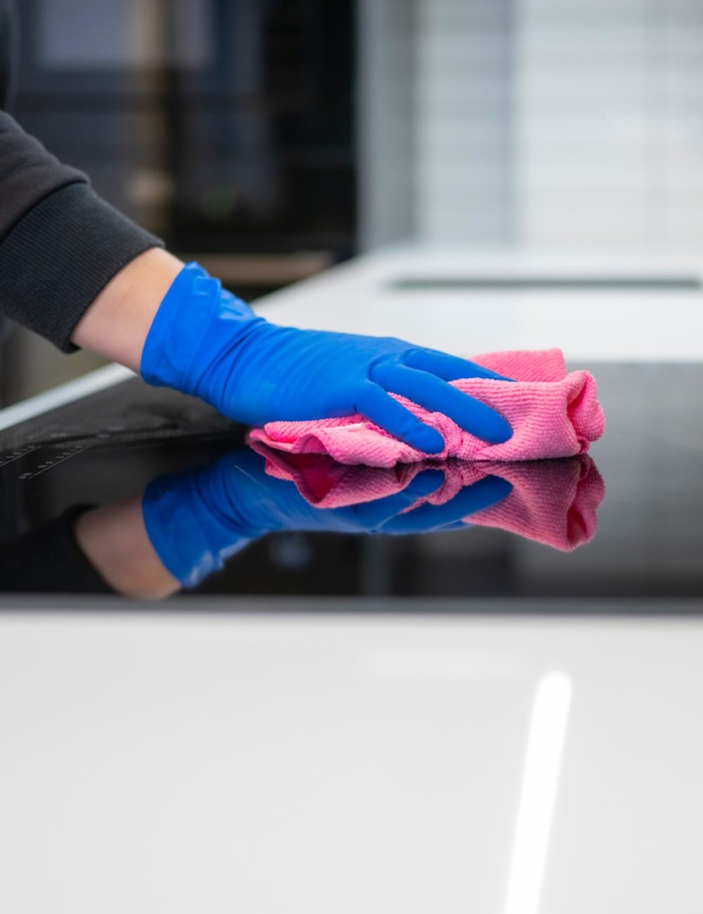 Close-up woman's hand wipes the electric stove with rag. Housekeeping cleaning concept